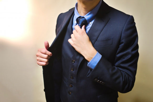 ネクタイをなおすスーツ姿の男性の写真